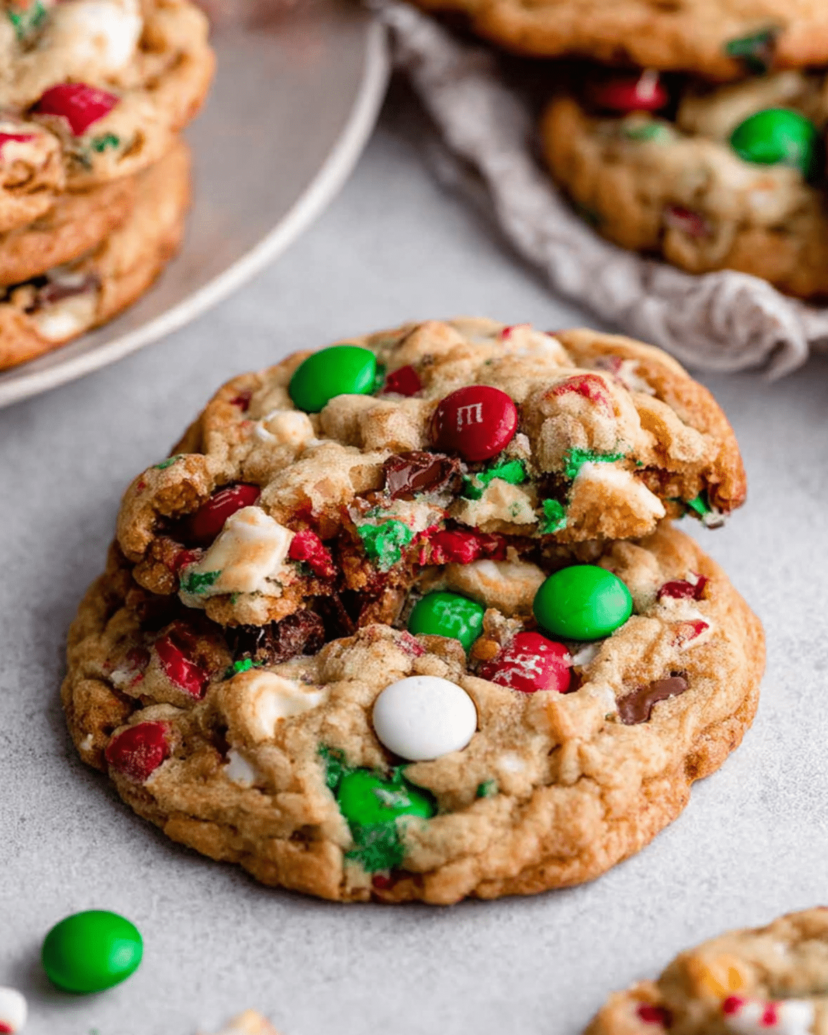 Christmas Kitchen Sink Cookies packed with red, green, and white candies, chocolate chips, and festive mix-ins on a light surface.