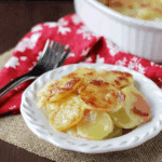 A serving of creamy scalloped potatoes with golden-brown tops on a white plate, made with Lactaid milk.