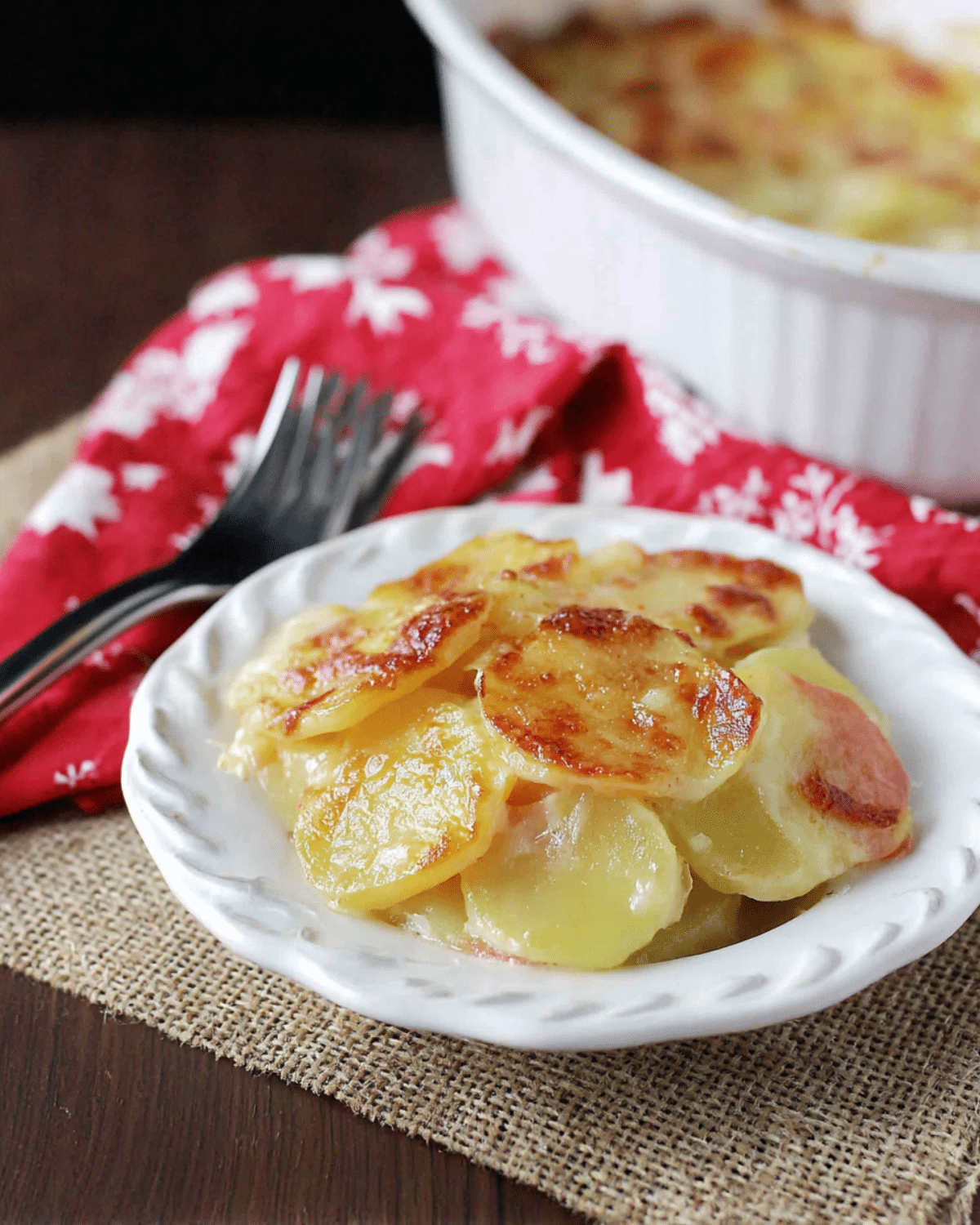 A serving of creamy scalloped potatoes with golden-brown tops on a white plate, made with Lactaid milk.