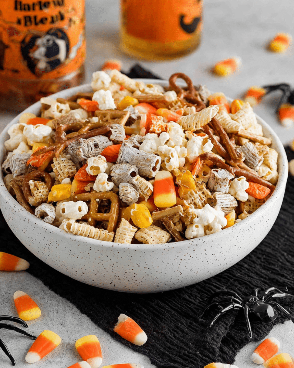 White bowl filled with easy Halloween snack mix including popcorn, pretzels, Chex cereal, candy corn, and festive treats.