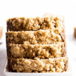 Easy pumpkin bread recipe with sweet crumb topping, sliced and stacked on a white rectangular plate.