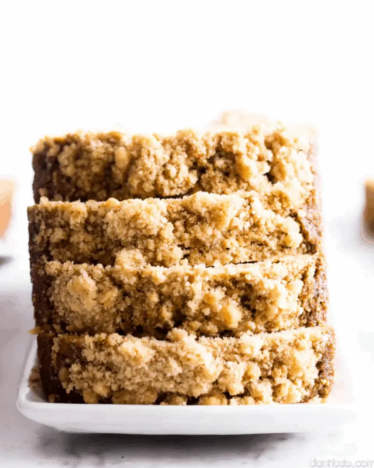 Easy pumpkin bread recipe with sweet crumb topping, sliced and stacked on a white rectangular plate.
