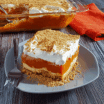 A slice of easy pumpkin delight topped with whipped cream and graham cracker crumbs, served on a gray plate.