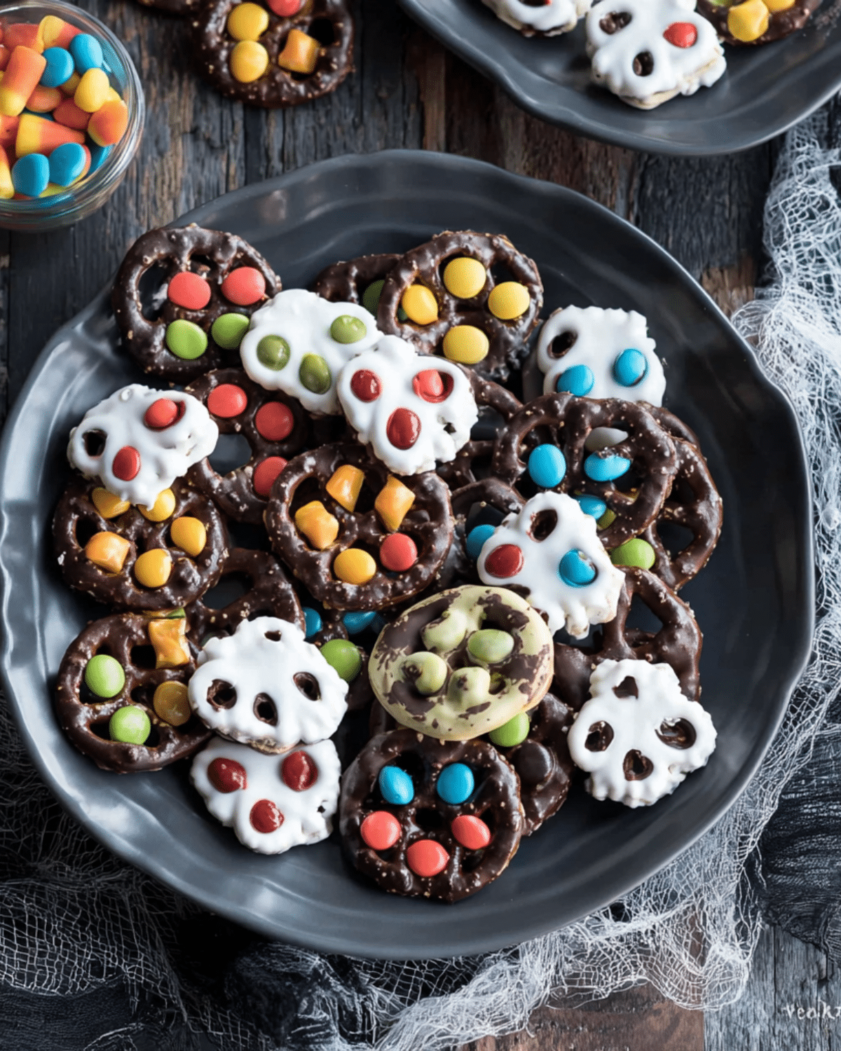 A plate of colorful Halloween pretzels decorated with white and dark chocolate and candy toppings.