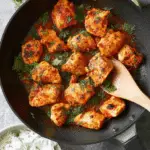 Skillet of Harissa Chicken with fresh herbs, served with a side of rice and lime.