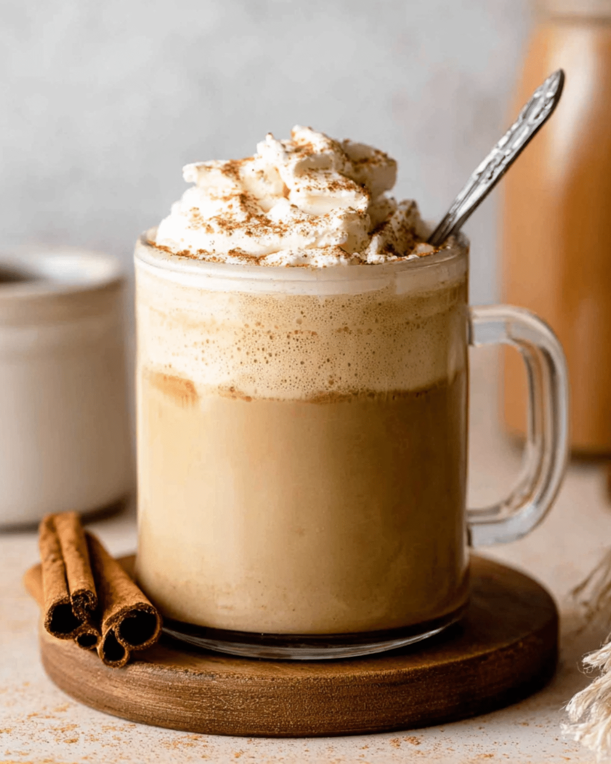 Glass mug filled with coffee topped with whipped cream and cinnamon, featuring homemade pumpkin spice coffee creamer.