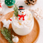 Melting Snowman Mocktail served in a glass with ice, garnished with a snowman figure, rosemary sprig, and festive decor.