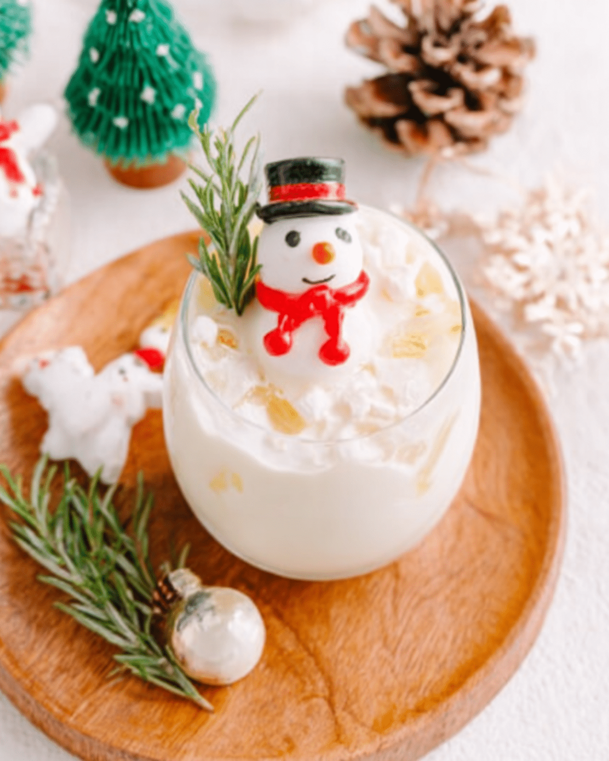 Melting Snowman Mocktail served in a glass with ice, garnished with a snowman figure, rosemary sprig, and festive decor.
