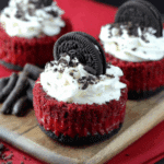 Mini Red Velvet Cheesecakes topped with whipped cream, crushed Oreo cookies, and whole Oreo cookies as garnish.