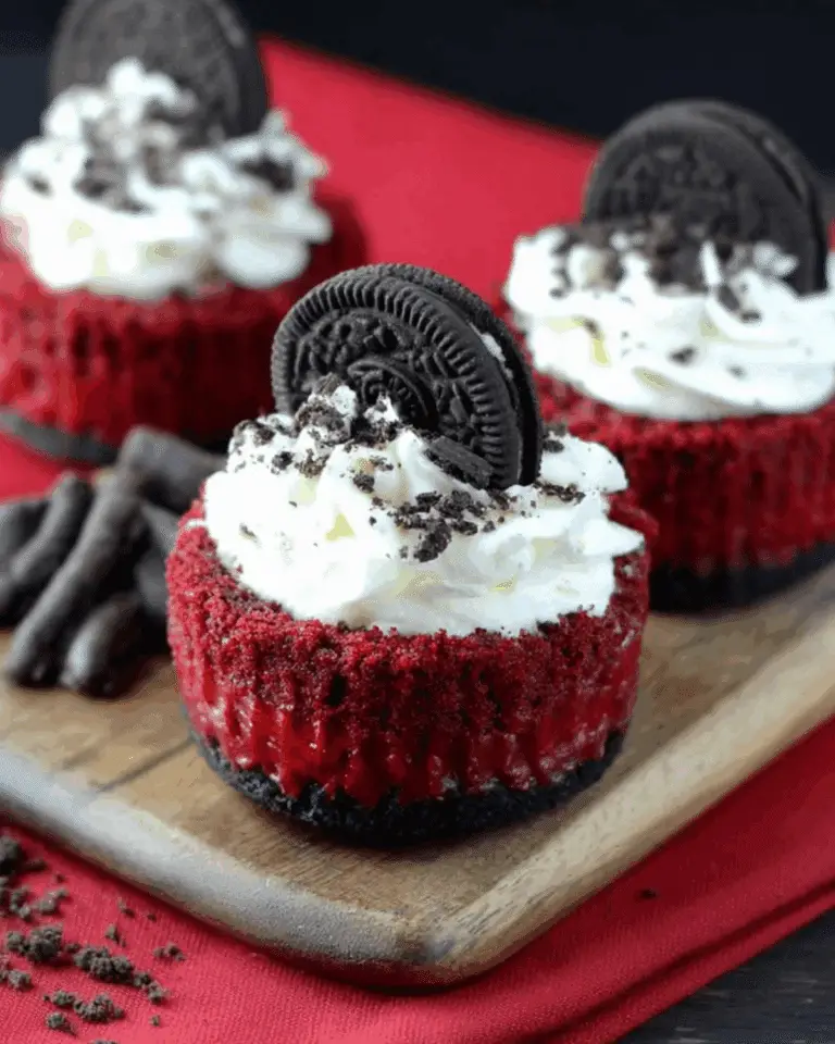 Mini Red Velvet Cheesecakes topped with whipped cream, crushed Oreo cookies, and whole Oreo cookies as garnish.