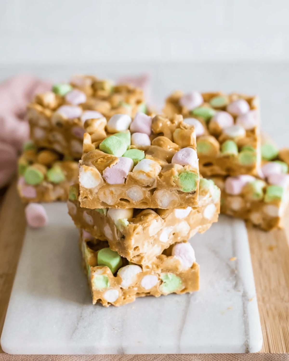 Stack of no bake butterscotch marshmallow bars with colorful mini marshmallows on a marble board.
