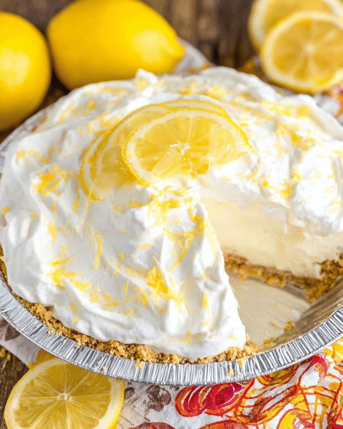 Creamy No bake Lemon Pie topped with whipped cream, lemon zest, and lemon slices in a graham cracker crust.