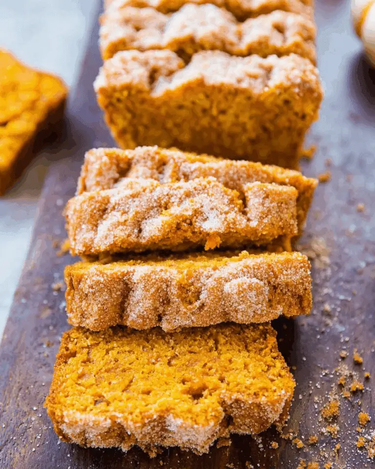 Pumpkin bread with cinnamon sugar topping, sliced and served on a wooden board.