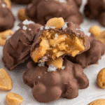 Close-up of salted peanut caramel clusters coated in chocolate, with gooey caramel and peanuts inside.