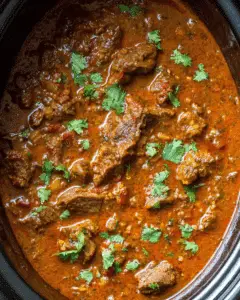 Slow cooker beef curry with tender beef chunks in a rich red curry sauce, garnished with fresh cilantro.