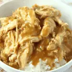 Bowl of slow cooker chicken and gravy served over white rice