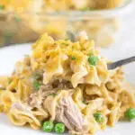 A serving of creamy tuna casserole with noodles, peas, and shredded tuna topped with golden breadcrumbs.