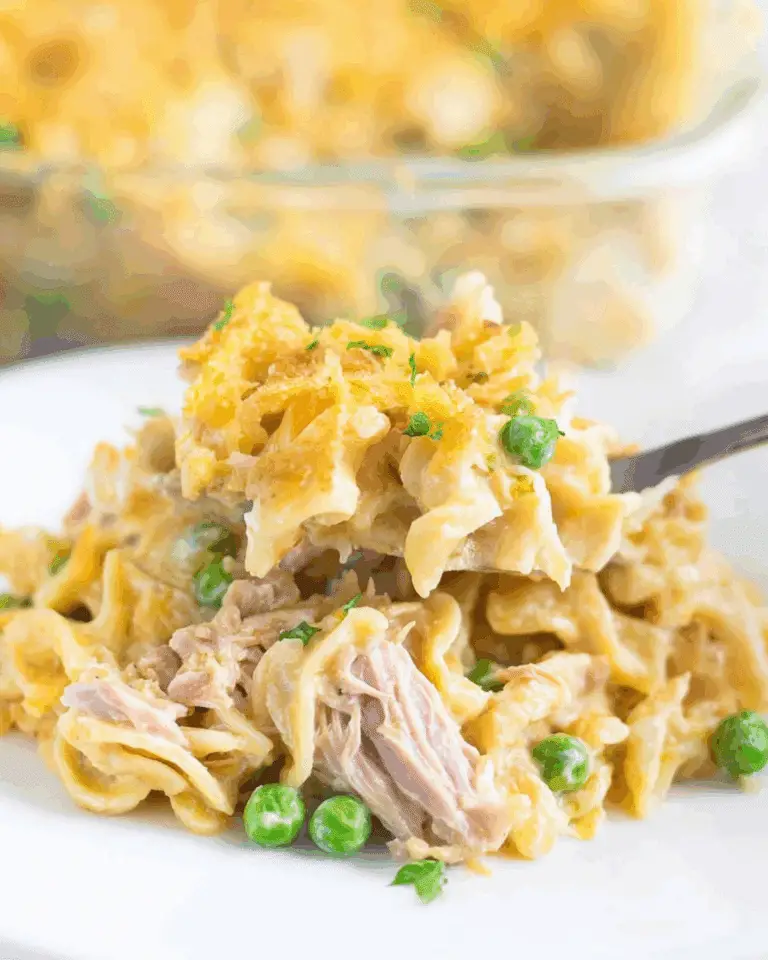 A serving of creamy tuna casserole with noodles, peas, and shredded tuna topped with golden breadcrumbs.