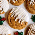 White Chocolate Dipped Chewy Maple Cookies topped with drizzled white chocolate and festive holly decorations nearby.