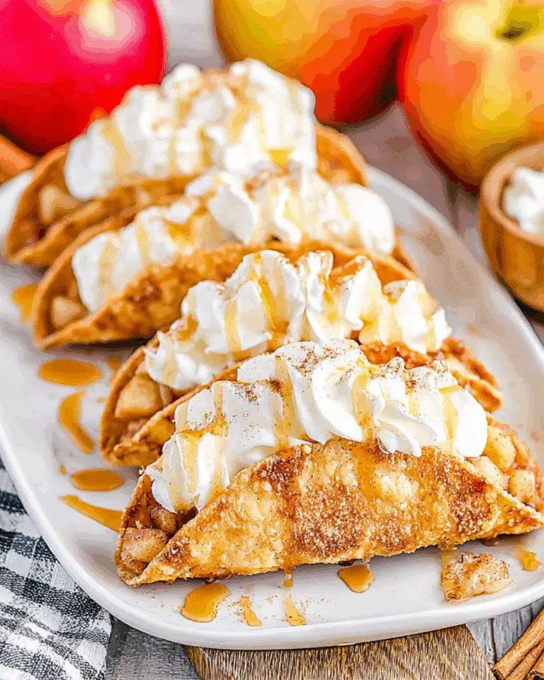 Crispy Apple Pie Tacos topped with whipped cream and caramel sauce, arranged on a white plate with fresh apples in the background.