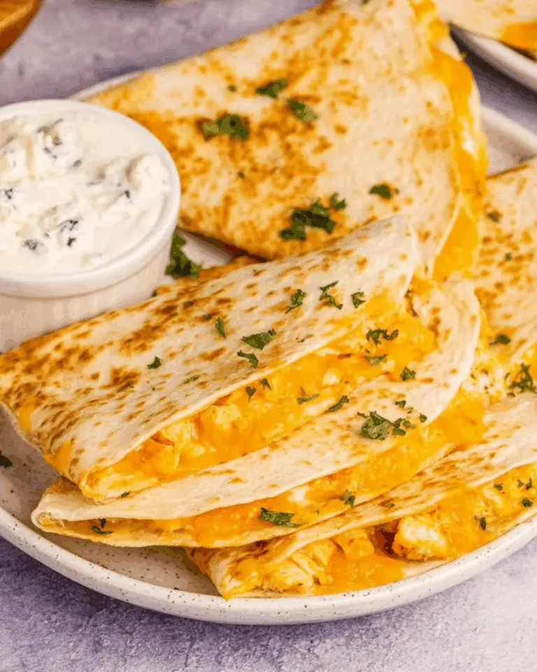 Plate of golden Air Fryer Buffalo Chicken Quesadillas filled with melted cheese and chicken, served with a side of creamy dipping sauce.