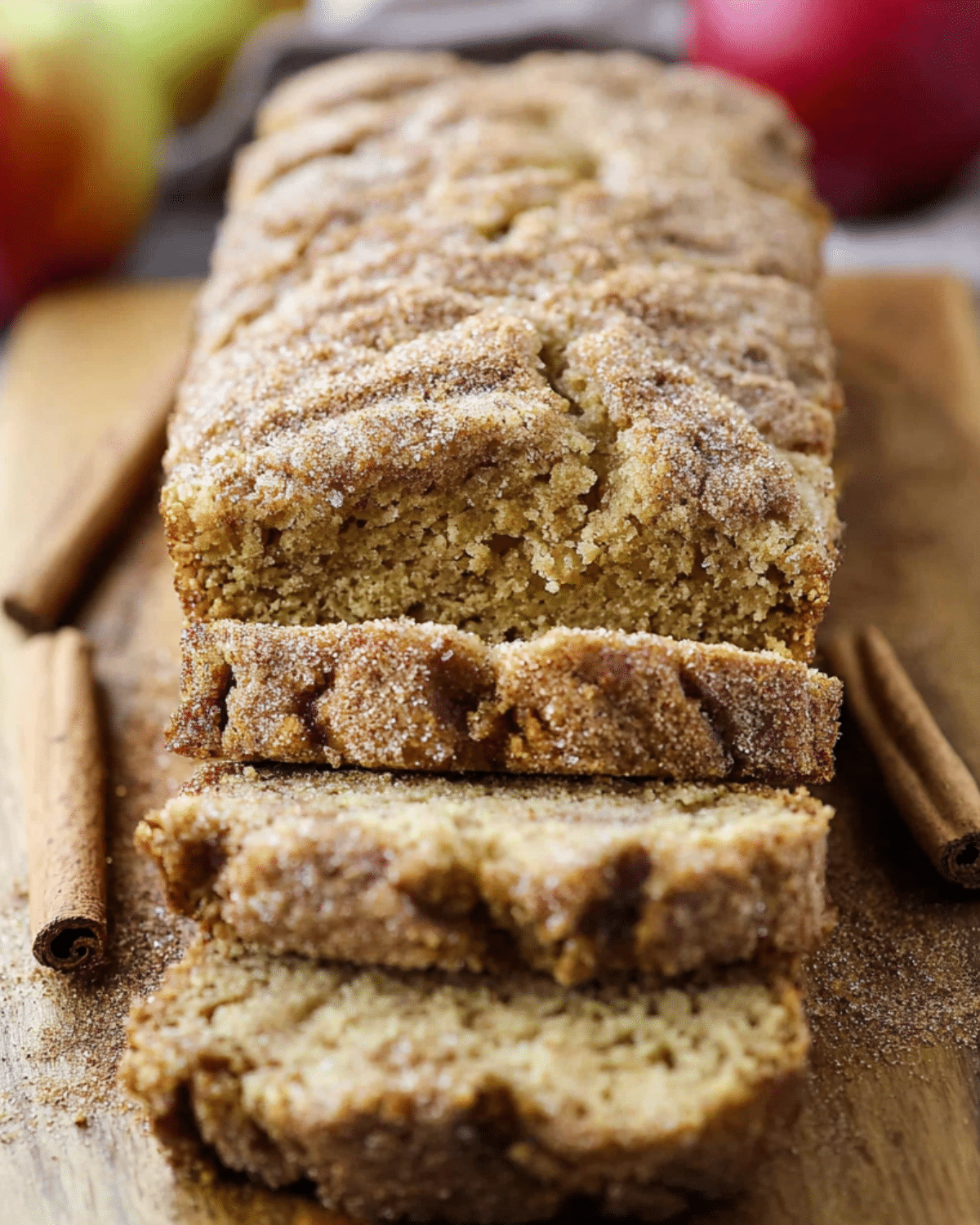 Close-up of sliced Apple Cider Donut Quick Bread on a wooden board with cinnamon sticks.