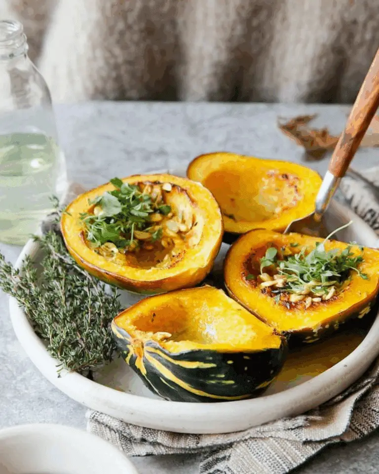 Halved Baked Acorn Squash served on a ceramic plate, garnished with microgreens and herbs.