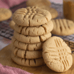 A stack of Classic Peanut Butter Cookies with signature crisscross fork marks, displayed on a wooden board.
