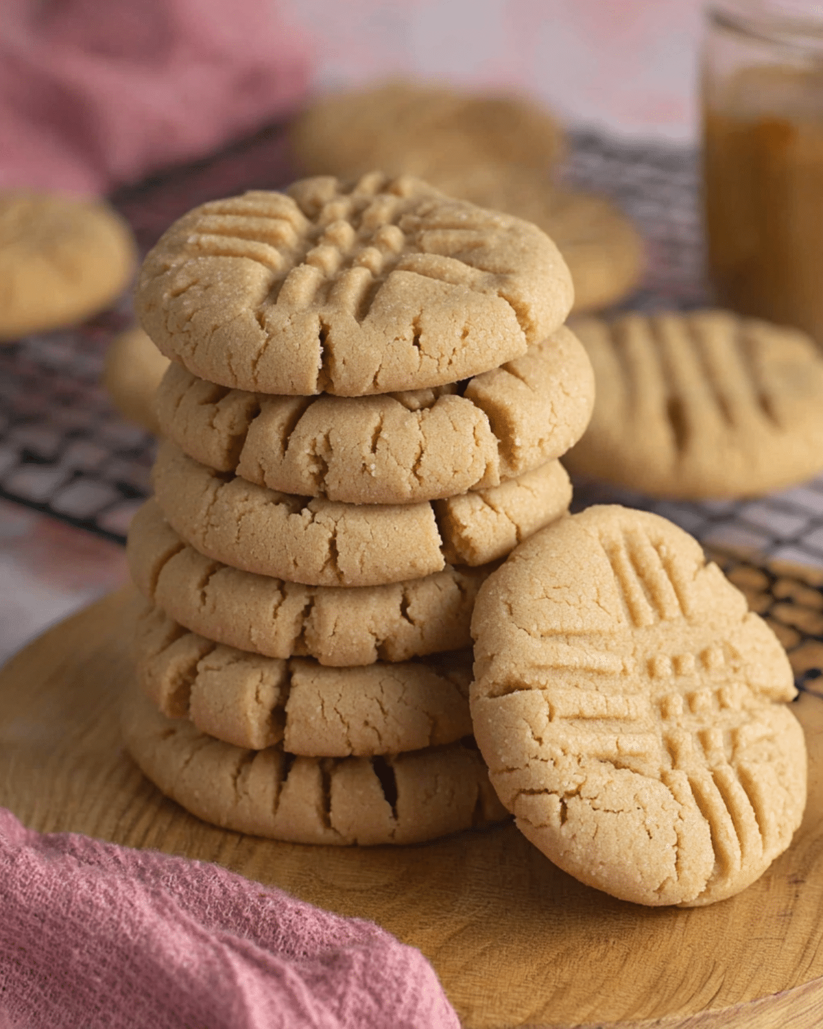 A stack of Classic Peanut Butter Cookies with signature crisscross fork marks, displayed on a wooden board.
