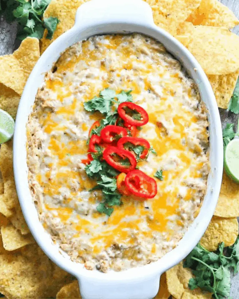 Cheesy Chicken Fajita Dip topped with red chili slices and cilantro, served with tortilla chips and lime wedges.