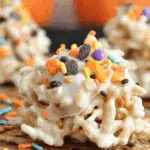 Close-up of Crockpot Halloween Haystacks covered in white chocolate and topped with colorful Halloween sprinkles.