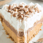 A slice of Layered Pumpkin Spice Jello Pie with a graham cracker crust, creamy layers, whipped topping, and pecan garnish.