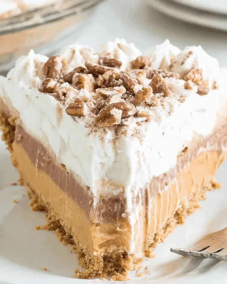 A slice of Layered Pumpkin Spice Jello Pie with a graham cracker crust, creamy layers, whipped topping, and pecan garnish.