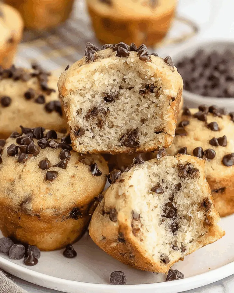 A plate of Mini Chocolate Chip Muffins, with one muffin cut open to reveal its soft, fluffy texture and chocolate chips inside.