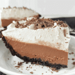 Slice of NO-BAKE CHOCOLATE PUDDING PIE with a chocolate cookie crust, creamy chocolate filling, whipped topping, and chocolate shavings.