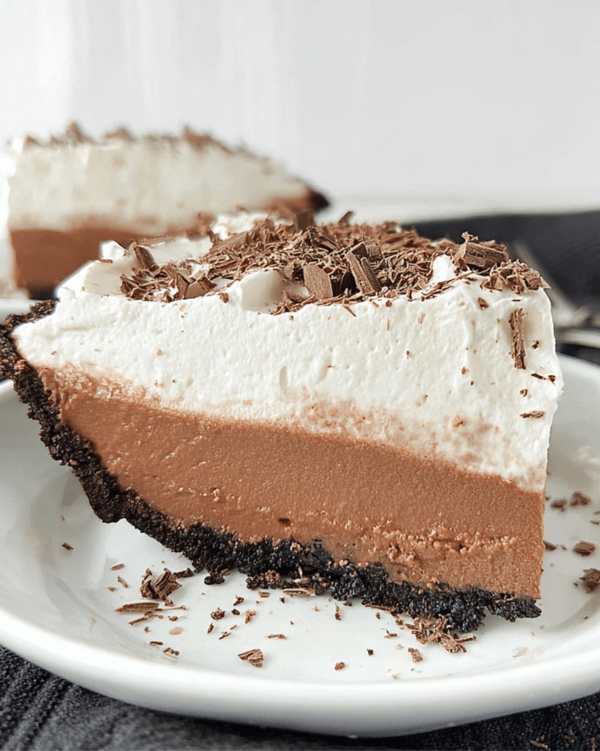 Slice of NO-BAKE CHOCOLATE PUDDING PIE with a chocolate cookie crust, creamy chocolate filling, whipped topping, and chocolate shavings.