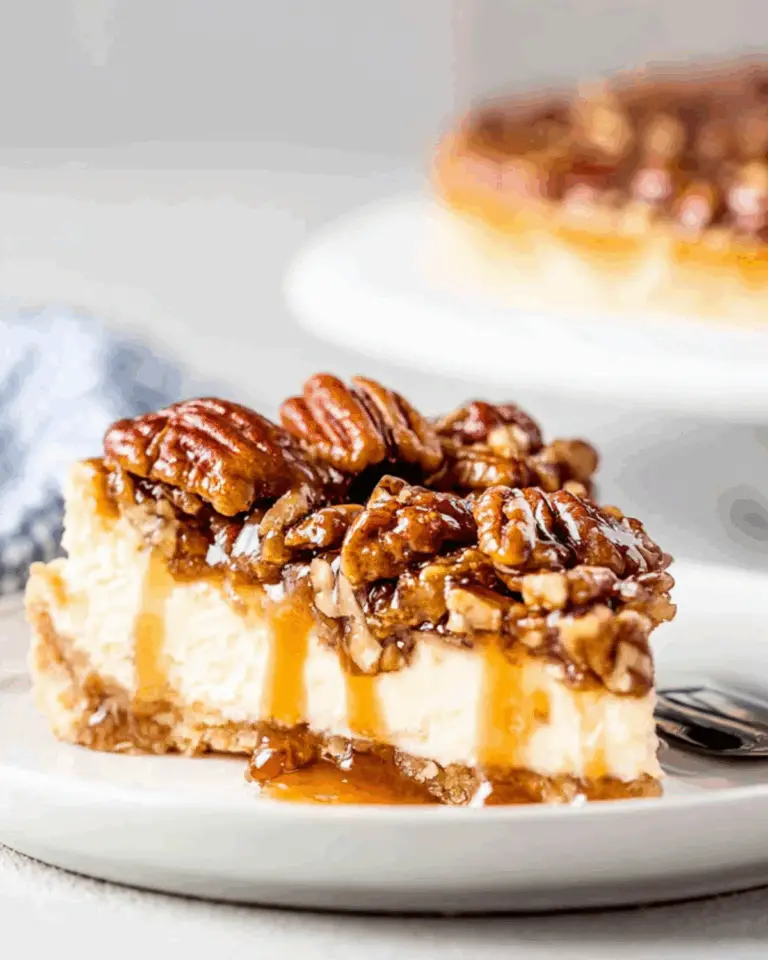 A slice of no-bake pecan pie cheesecake topped with glazed pecans and caramel sauce, served on a white plate.