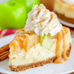 A slice of No Bake Apple Cheesecake topped with whipped cream, caramel drizzle, and cinnamon, served on a white plate.