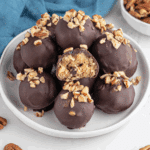Pecan pie balls coated in chocolate, topped with chopped pecans, and filled with a soft pecan and cookie mixture.