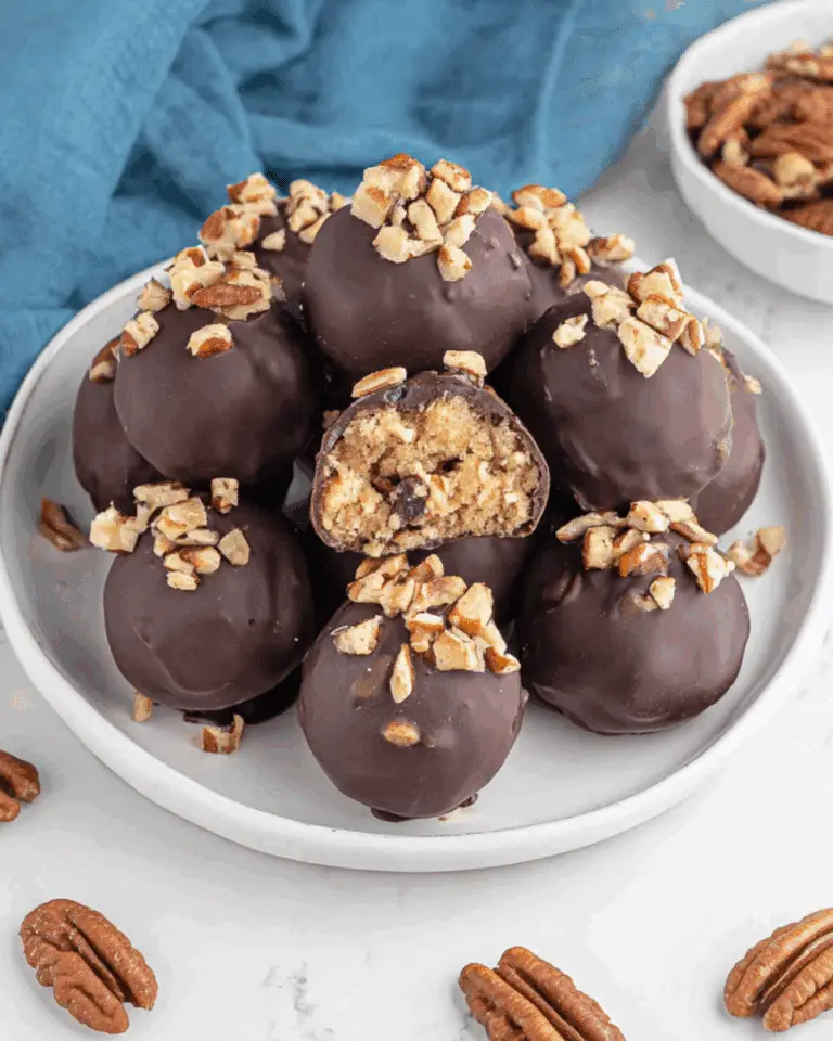 Pecan pie balls coated in chocolate, topped with chopped pecans, and filled with a soft pecan and cookie mixture.