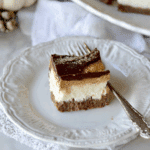 A close-up of a Pumpkin Chocolate Cheesecake Bar on a vintage white plate with a fork.