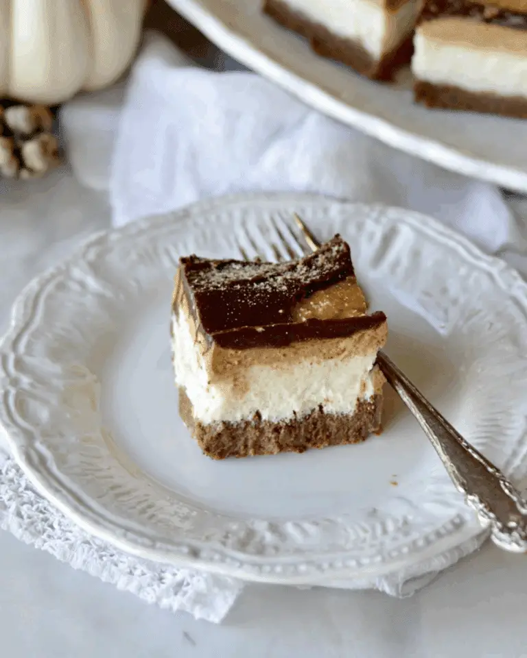 A close-up of a Pumpkin Chocolate Cheesecake Bar on a vintage white plate with a fork.