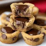 A plate stacked with Reese’s Chocolate Chip Cookie Bites filled with melted chocolate centers.