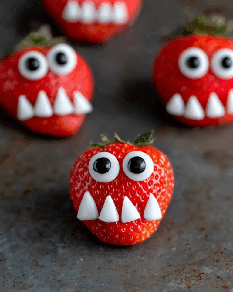 Fresh strawberries decorated as Strawberry Monsters with candy eyes and pointed white candy teeth.