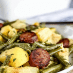 Sausage green bean potato casserole with golden potatoes, tender green beans, and slices of browned sausage served in a white dish.