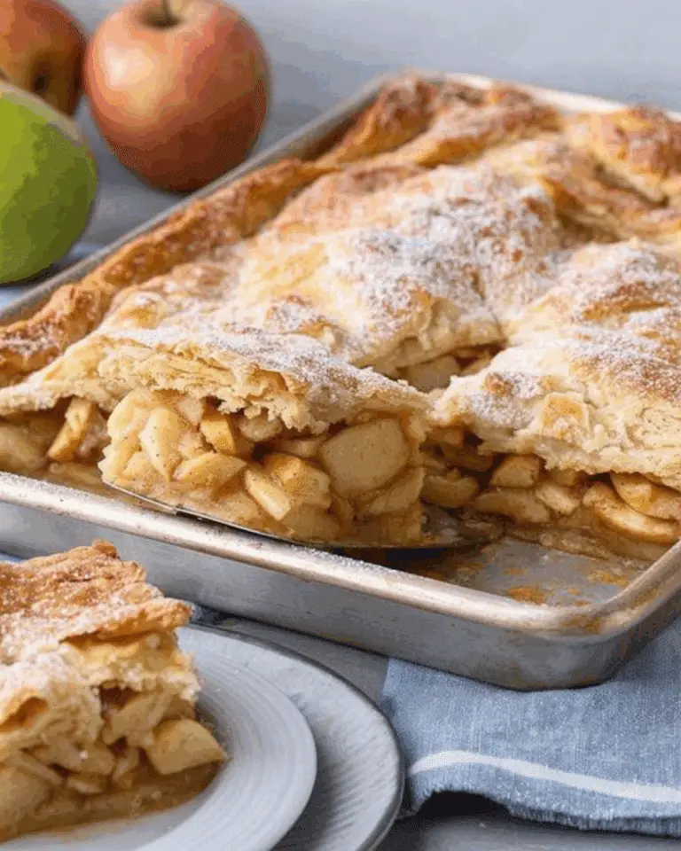 Sheet Pan Apple Pie with a golden, flaky crust and cinnamon-spiced apple filling, served with a slice on a white plate.