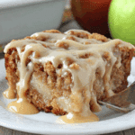 A slice of apple dapple cake drizzled with rich caramel glaze on a white plate.
