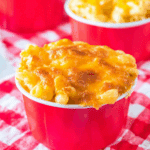 A red cup filled with Copycat Chick-fil-A Mac & Cheese topped with golden, melted cheddar cheese.