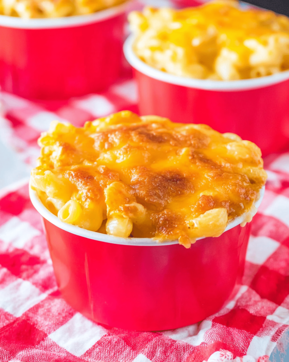 A red cup filled with Copycat Chick-fil-A Mac & Cheese topped with golden, melted cheddar cheese.