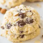 Close-up of soft Almond Joy cookies loaded with melted chocolate chunks, coconut flakes, and slivered almonds.